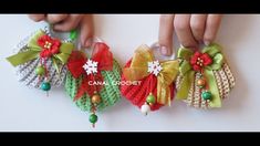 two hands are holding small christmas bells made out of knitted material and ribbons with bows on them