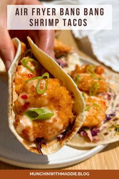 a person holding a fish taco in their hand with the words air fryer bang bang shrimp tacos