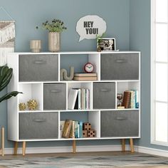 a white bookcase with grey storage bins