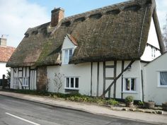 a white house with a thatched roof next to a street