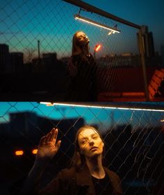 a woman standing behind a chain link fence with her hands up in the air and looking up