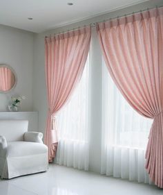 a living room with white furniture and pink curtains on the windowsill, along with a mirror