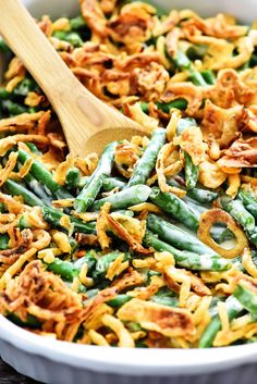 green bean and onion casserole in a white bowl with a wooden serving spoon