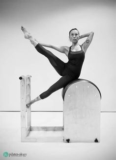 black and white photograph of a ballerina on top of a wooden structure with her arms stretched out