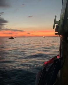 the sun is setting over the ocean and boats are in the water