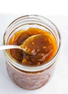 a spoon in a jar filled with caramel sauce