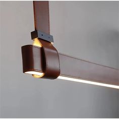 a close up of a light fixture on a wall with a leather strap hanging from it