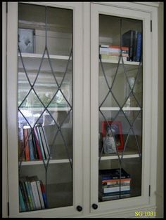 a bookcase with two glass doors and books on the bottom shelf in front of it