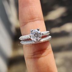 a close up of a person's hand holding a ring with a diamond on it