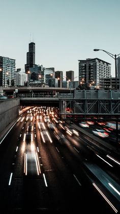 the city skyline is lit up at night with light streaks on the road and buildings in the background