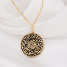 a gold plated necklace with an intricate design on the front and back, hanging from a golden chain