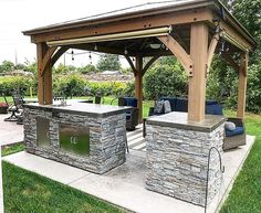 an outdoor kitchen with grill and seating area in the middle of a grassy yard next to a covered patio