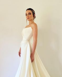 a woman in a white wedding dress posing for the camera with her hands on her hips