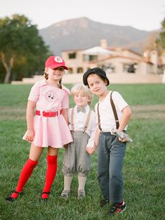 three children are standing in the grass together