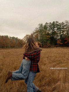 a man and woman are hugging in the middle of a field