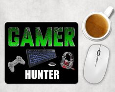 a computer mouse and keyboard with the words gamer hunter on it next to a cup of coffee