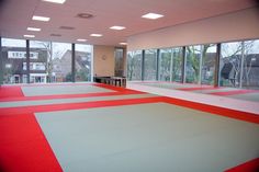 an empty room with red and white mats in front of large windows, looking out onto the street