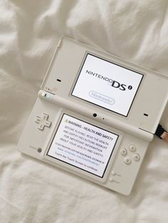 an old nintendo ds game system laying on top of a white sheet with the words nintendo ds printed on it