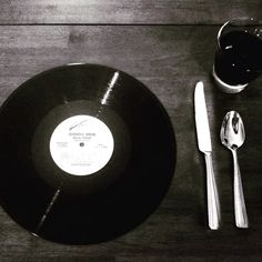 a black record sitting on top of a wooden table next to silverware and spoons