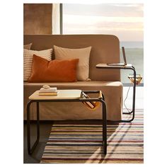 a living room with a couch, coffee table and window overlooking the ocean at sunset