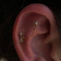 a close up of a person's ear with a chain attached to the side