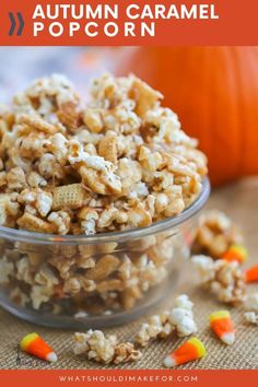 a glass bowl filled with popcorn and candy on top of a table next to an orange pumpkin