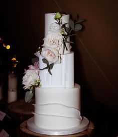 a three tiered white wedding cake with flowers on top