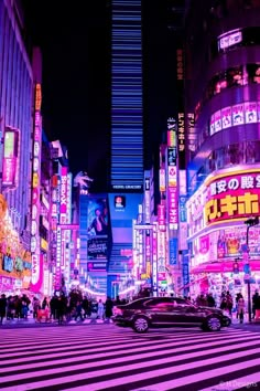 a city street filled with lots of tall buildings and neon signs at night time in tokyo, japan