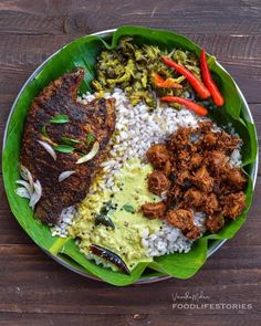 a plate with rice, meat and vegetables on it sitting on top of a wooden table