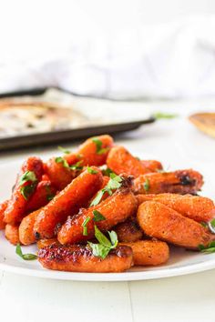 a white plate topped with carrots covered in ketchup and garnish