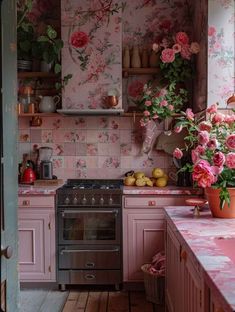 a kitchen with pink floral wallpaper and an old stove top oven in the corner