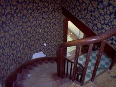 the stairs are made of wood and have blue wall paper on them, with a checkered floor