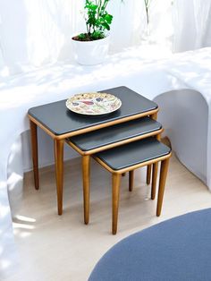 three small tables with plates on them in front of a white tablecloth and potted plant