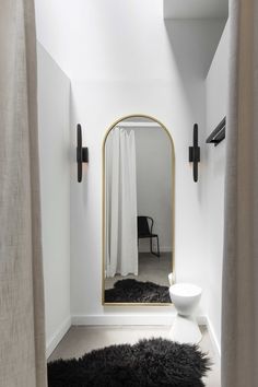 a bathroom with a large mirror and black rug