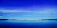 the sky is blue and there are some clouds in the distance over the water with a boat out on it