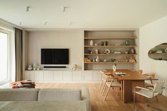 a living room filled with furniture and a flat screen tv mounted on a wall above a wooden dining table