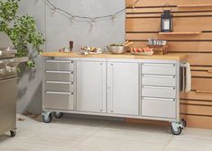 an outdoor kitchen with stainless steel cabinetry and wood counter tops, along with potted plants