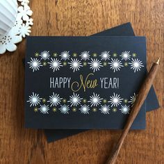 a happy new year greeting card on top of a wooden table next to a candle