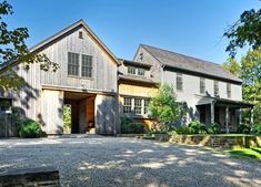 a large house sitting in the middle of a lush green field next to a forest