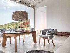 a dining room table with chairs and a basket hanging from it's ceiling next to a large window