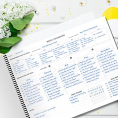 an open planner sitting on top of a table next to flowers