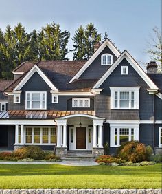 a large blue house with white trim and lots of windows on the front, along with green grass