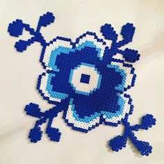 a blue and white flower made out of perler beads on top of a table