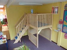 there is a wooden staircase in the corner of this children's playroom that has purple carpet and yellow walls