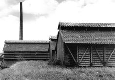 black and white photograph of an old farm house in rural area with smokestack