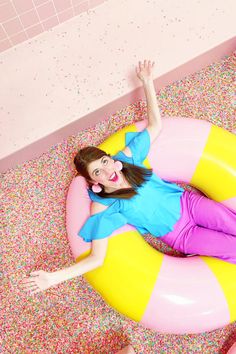 a woman laying on top of an inflatable pool float with sprinkles