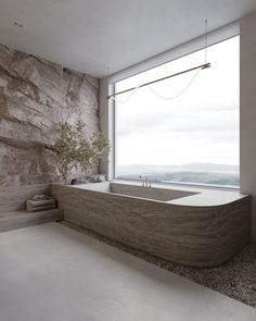 a bathroom with a large stone wall next to a bathtub in front of a window