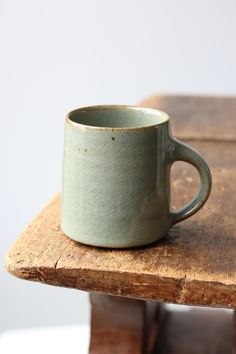 a coffee cup sitting on top of a wooden table next to a piece of wood