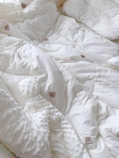 an unmade bed with white sheets and buttons on the comforter is seen in this image