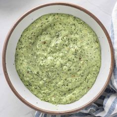 a white bowl filled with green sauce on top of a blue and white striped napkin